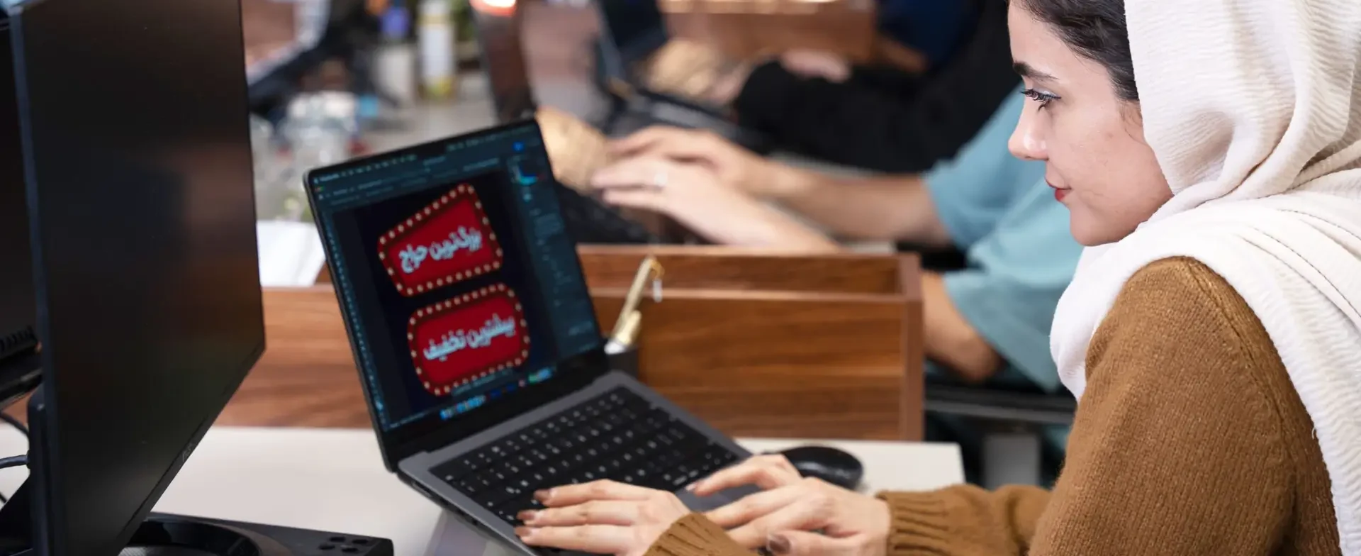 همکار اکالا در حال طراحی گرافیک کمپین تبلیغاتی روی لپ‌تاپ – خلاقیت، کیفیت خدمات، جلب رضایت مشتری | Okala team member designing advertising campaign graphics on laptop – creativity, service quality, customer satisfaction